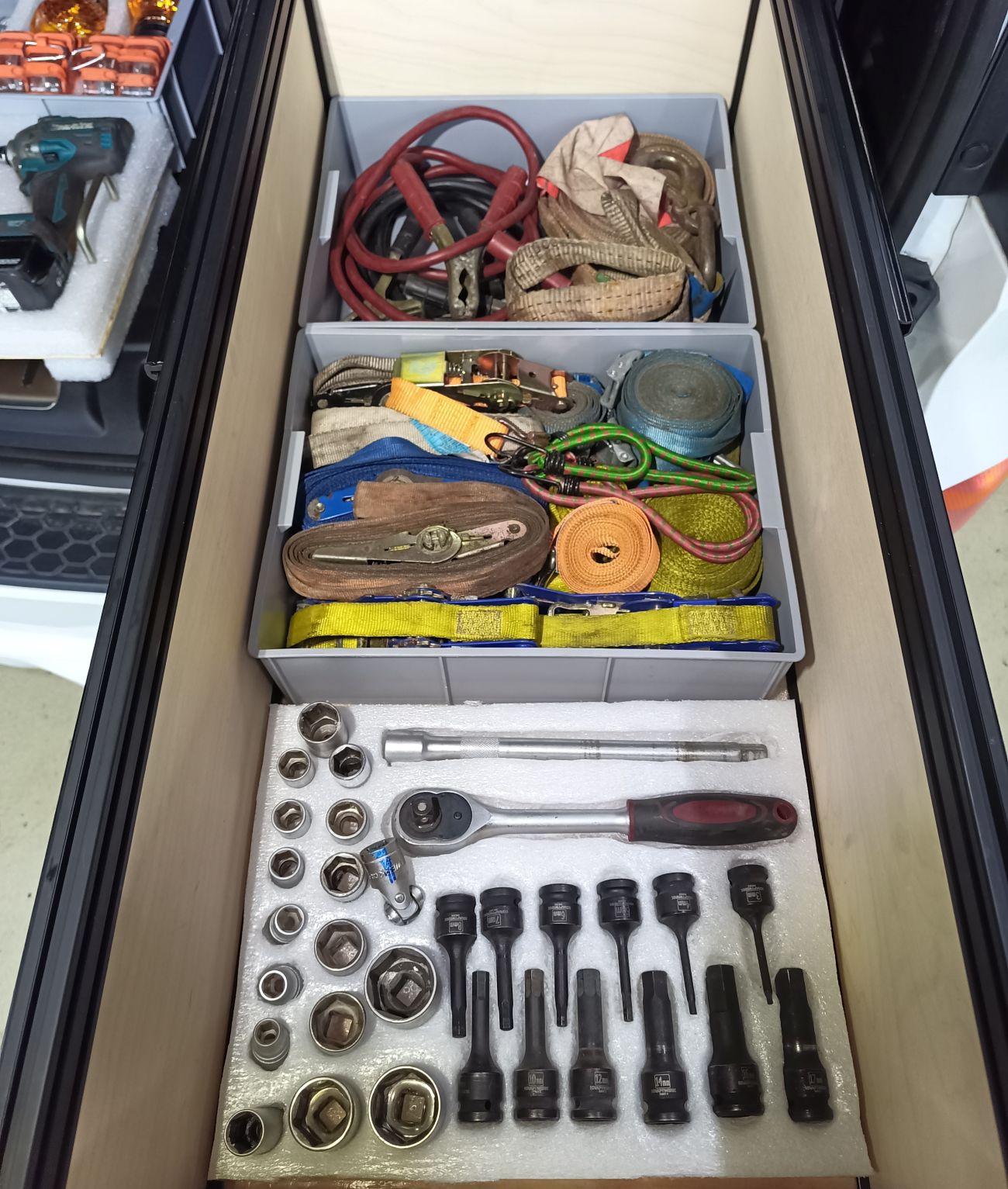 Sockets, wrenches, and tools arranged inside an open cargo drawer